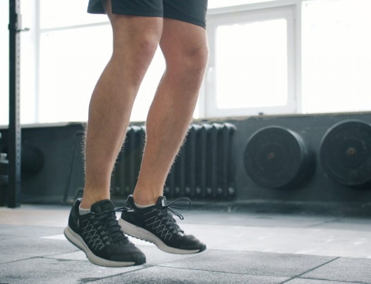 Tilt-up of sporty man jumping with skipping rope in gym working out alone busy with cardio exercise. Healthy lifestyle, people and active youth concept.